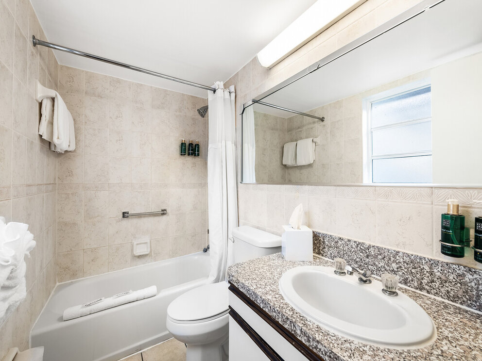 A clean bathroom with a granite countertop, large mirror, and tiled walls